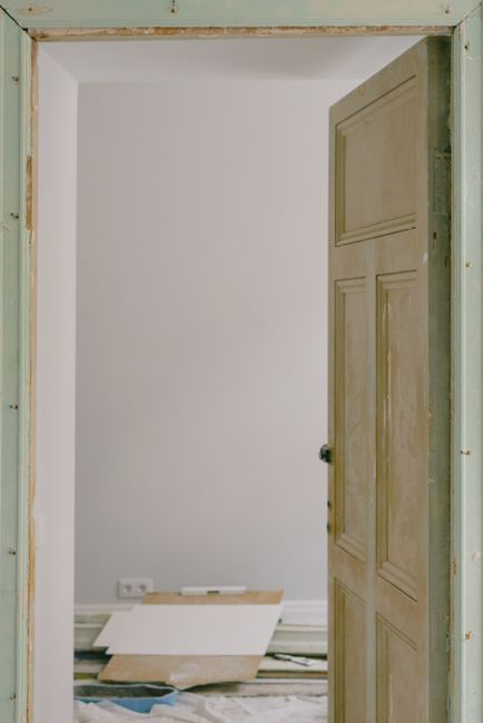 Wooden door in room with pile of construction materials at home during renovation process