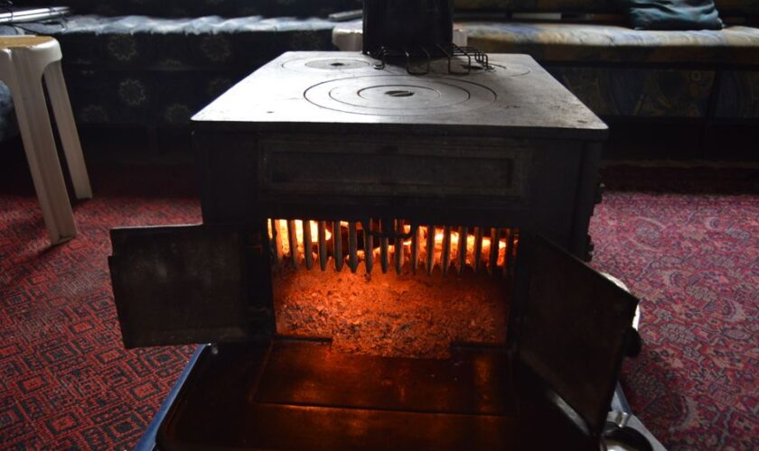 A classic vintage wood heater radiating warmth in a cozy, carpeted interior room.