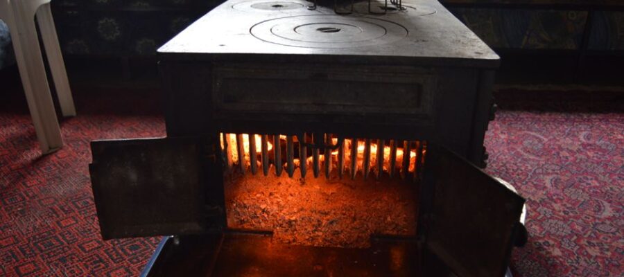 A classic vintage wood heater radiating warmth in a cozy, carpeted interior room.