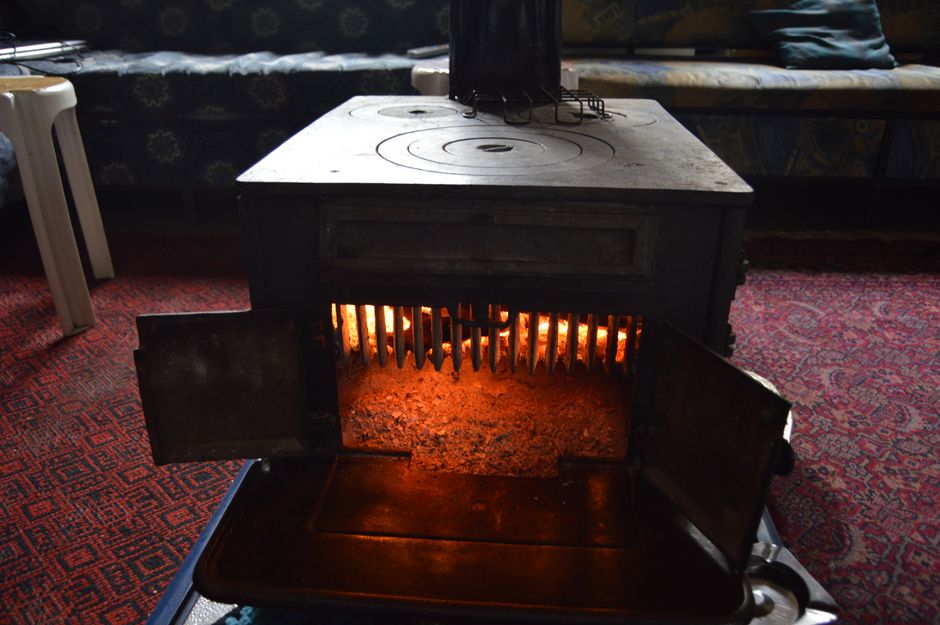 A classic vintage wood heater radiating warmth in a cozy, carpeted interior room.