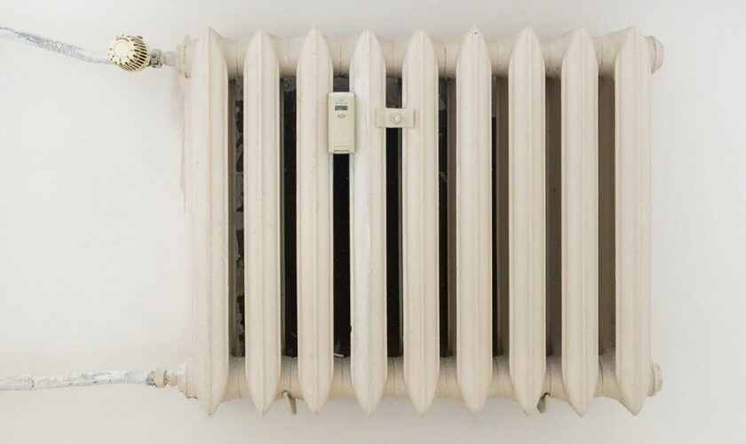 A classic white metal radiator on a plain wall, showcasing minimalist interior design.