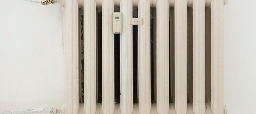 A classic white metal radiator on a plain wall, showcasing minimalist interior design.