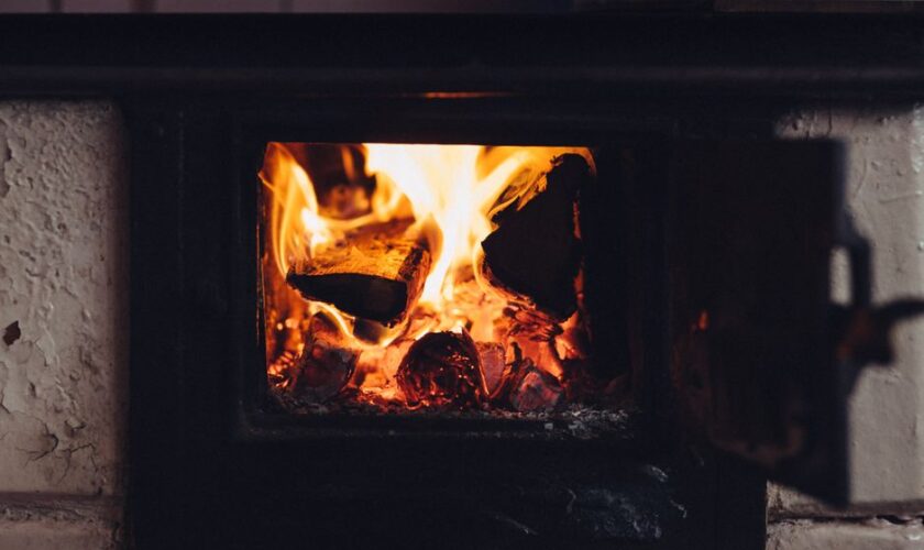 A close-up of a wood-burning fireplace emitting warmth with flickering flames and glowing embers.