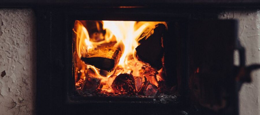 A close-up of a wood-burning fireplace emitting warmth with flickering flames and glowing embers.