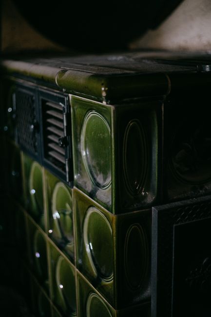 A close-up of vintage green ceramic tiles on a traditional masonry stove, showcasing retro design.