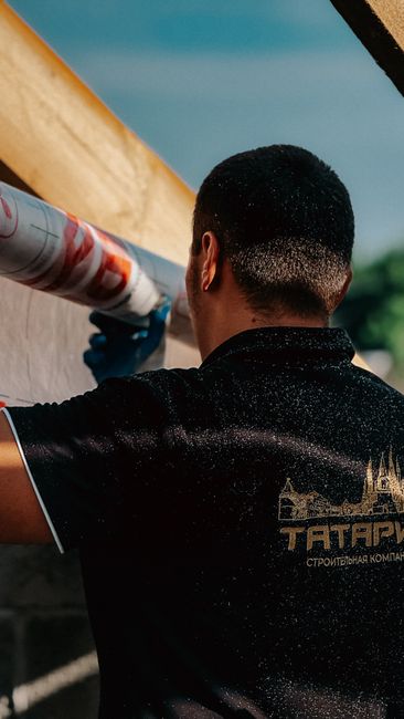 A construction worker installs roofing insulation on a sunny day, showcasing professional craftsmanship.
