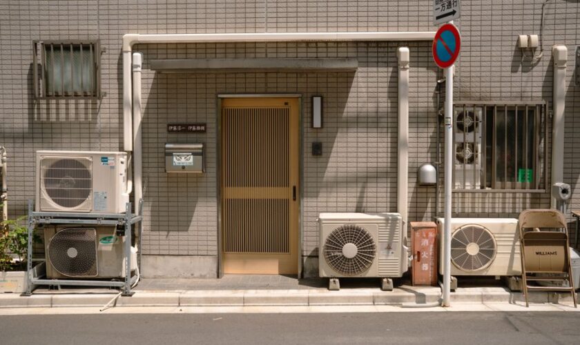A minimalist facade with air conditioners and a no parking sign in Tokyo, Japan.