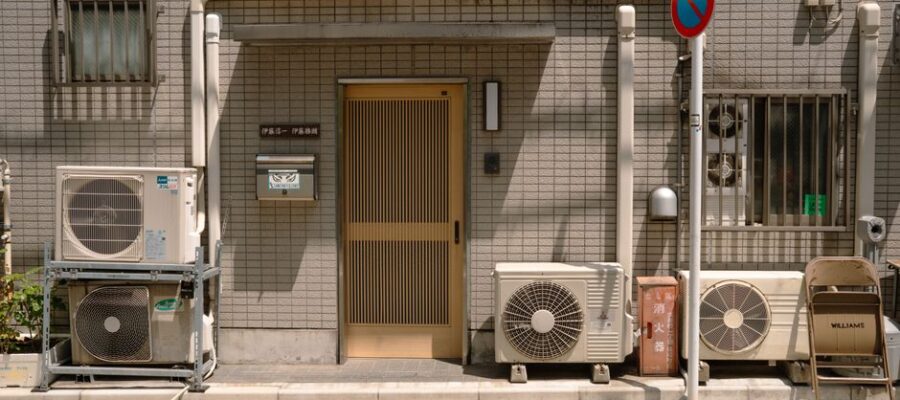 A minimalist facade with air conditioners and a no parking sign in Tokyo, Japan.
