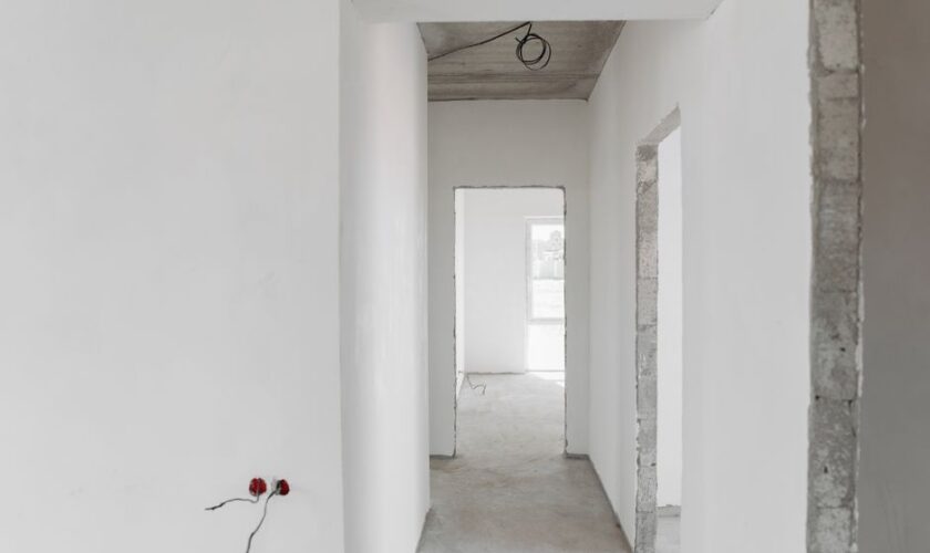 A minimalist view of an unfinished building interior with white walls and door frames.