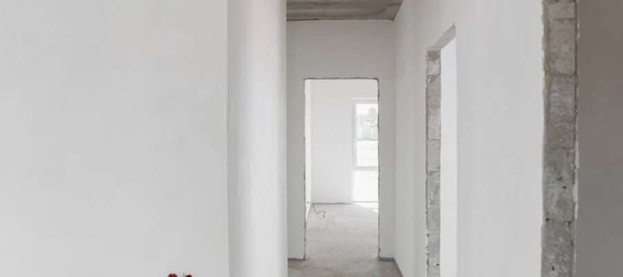 A minimalist view of an unfinished building interior with white walls and door frames.