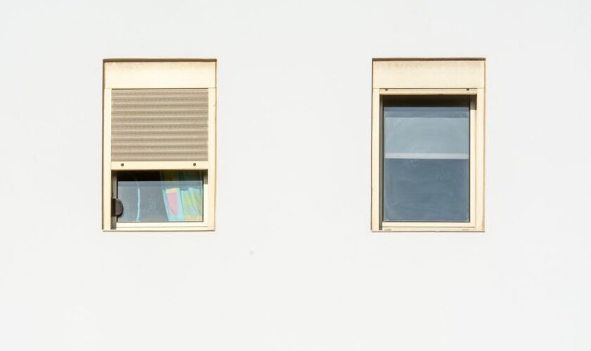 A minimalistic facade featuring two modern windows with shutters in a bright, contemporary style.