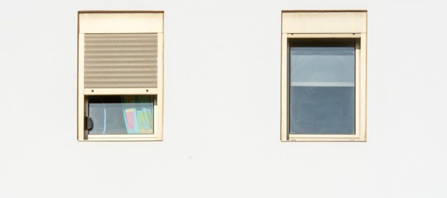 A minimalistic facade featuring two modern windows with shutters in a bright, contemporary style.