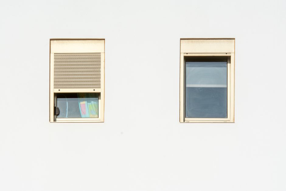 A minimalistic facade featuring two modern windows with shutters in a bright, contemporary style.