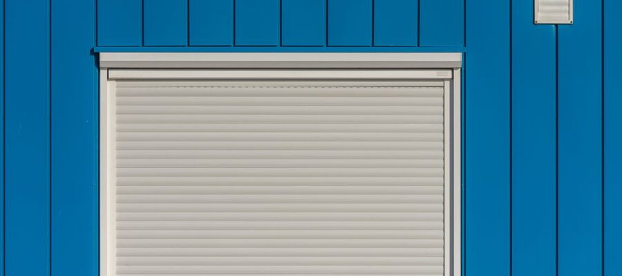 A modern blue wall with a closed white roller shutter, perfect for architectural designs.