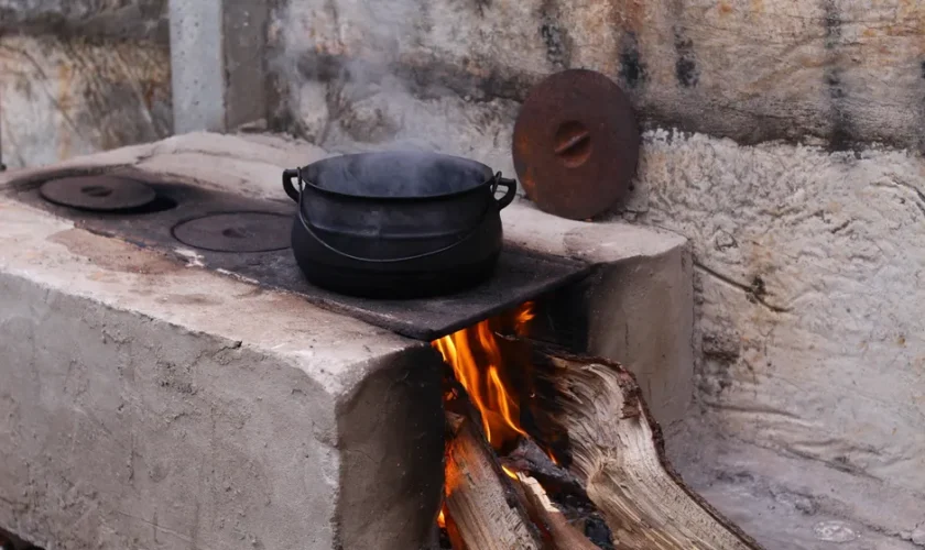A rustic wood-fired stove in Goiânia, Brazil, with a steaming pot on an open flame.