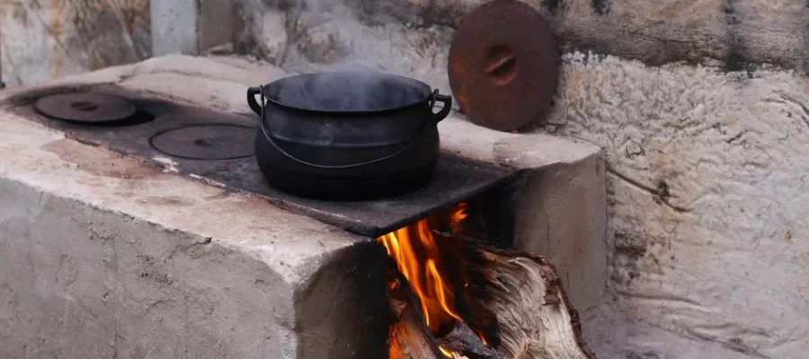 A rustic wood-fired stove in Goiânia, Brazil, with a steaming pot on an open flame.
