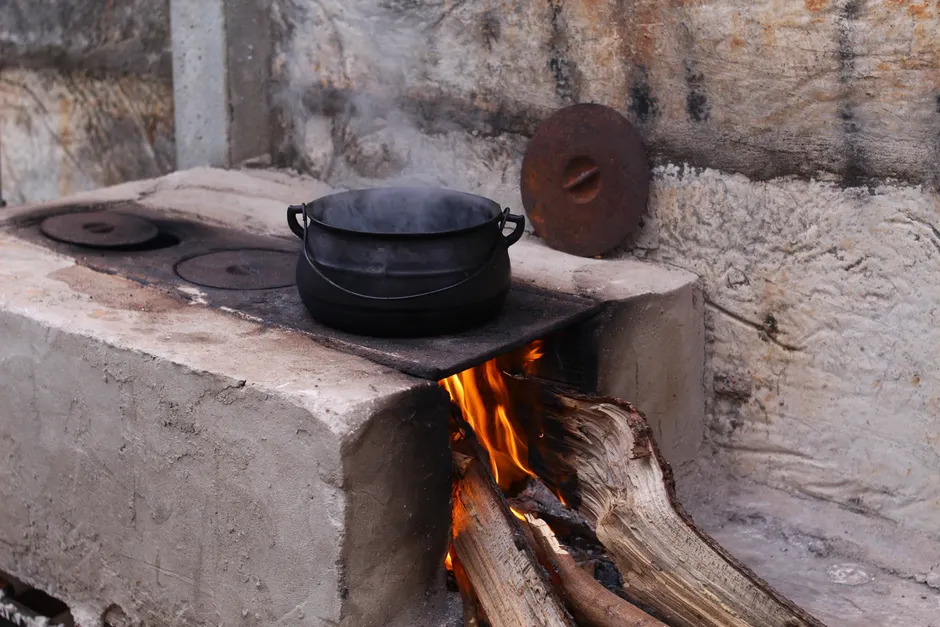 A rustic wood-fired stove in Goiânia, Brazil, with a steaming pot on an open flame.