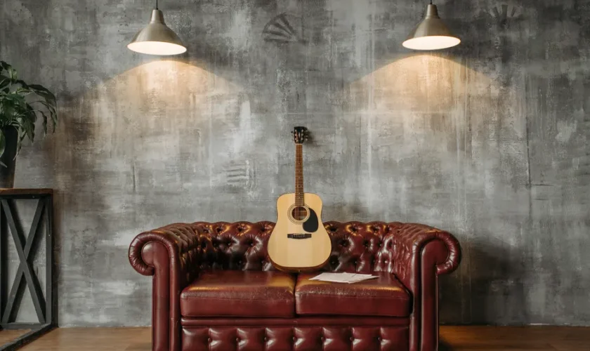 A stylish interior design featuring an acoustic guitar resting on a red leather sofa with pendant lighting.