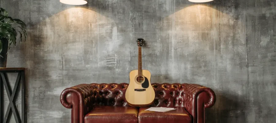 A stylish interior design featuring an acoustic guitar resting on a red leather sofa with pendant lighting.
