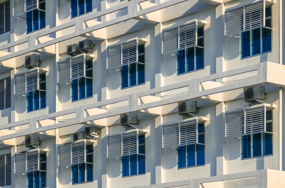 Architectural detail of a modern building facade with glass windows and air conditioners.
