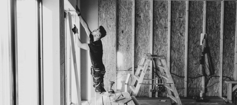 Black and white photo of a worker installing drywall indoors, Falun, Sweden.