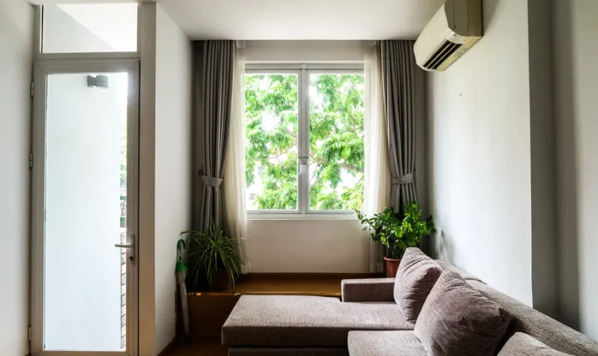 Bright living room with a cozy sofa, indoor plants, and a large window with curtains.