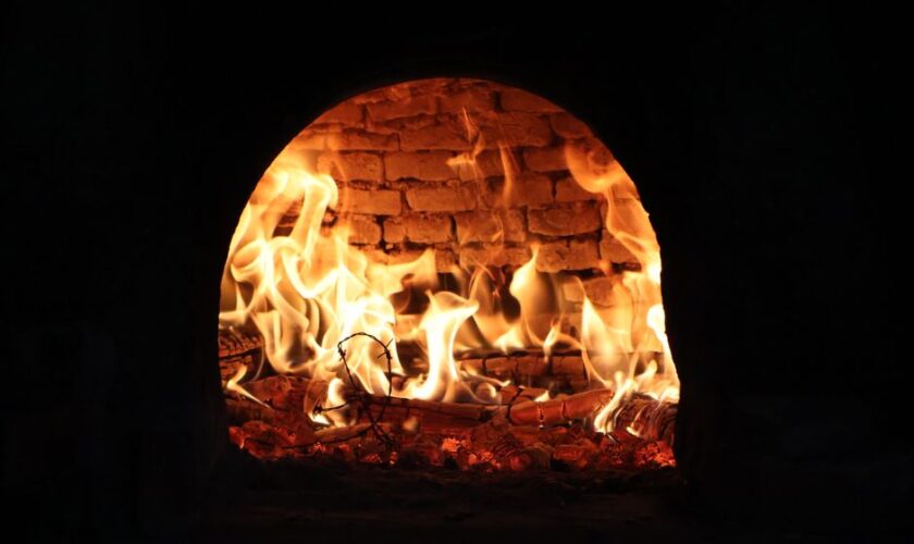Captivating image of a roaring fire inside a traditional wood-fired oven, exuding warmth and rustic charm.