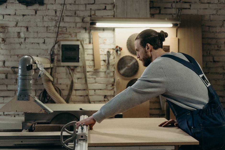 Carpenter expertly operating a sliding table saw in a rustic woodworking workshop.