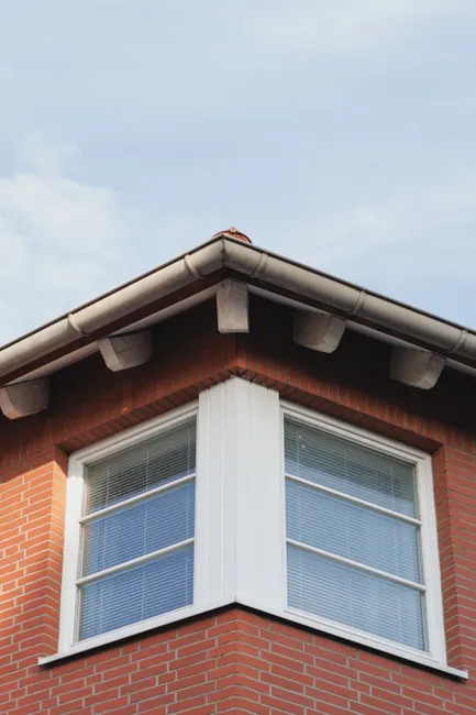Close-up of a brick house corner with windows against a blue sky in Hildesheim, Germany.