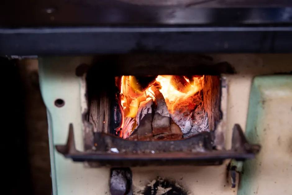 Close-up of a burning firewood in a vintage stove, providing warmth and nostalgia.
