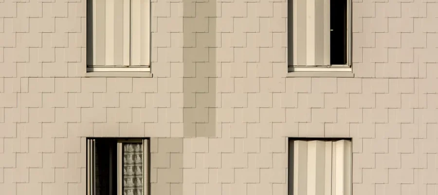 Close-up of a modern apartment building facade with symmetrical windows and beige cladding.