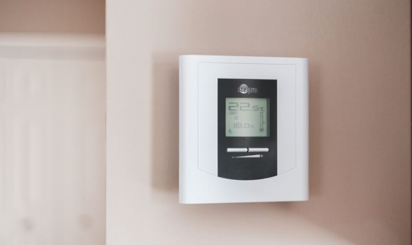 Close-up of a modern digital thermostat mounted on a wall, displaying temperature settings in Celsius.