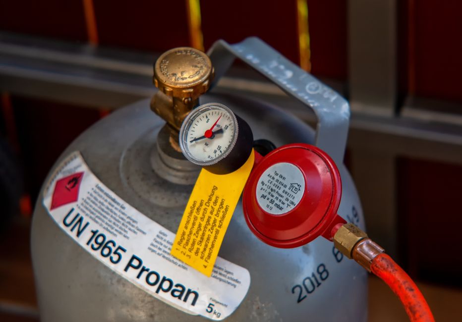 Close-up of a propane gas cylinder with pressure gauge and regulator, ideal for safety and equipment use.