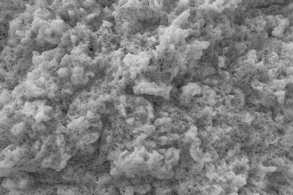 Close-up of a textured surface resembling snow or foam in black and white.