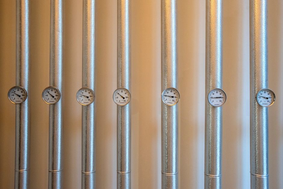 Close-up of industrial silver metal ducts with white dial gauges.