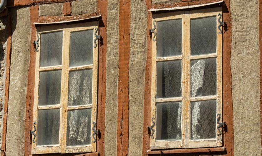 Close-up of rustic vintage windows with wooden frames on a traditional facade.