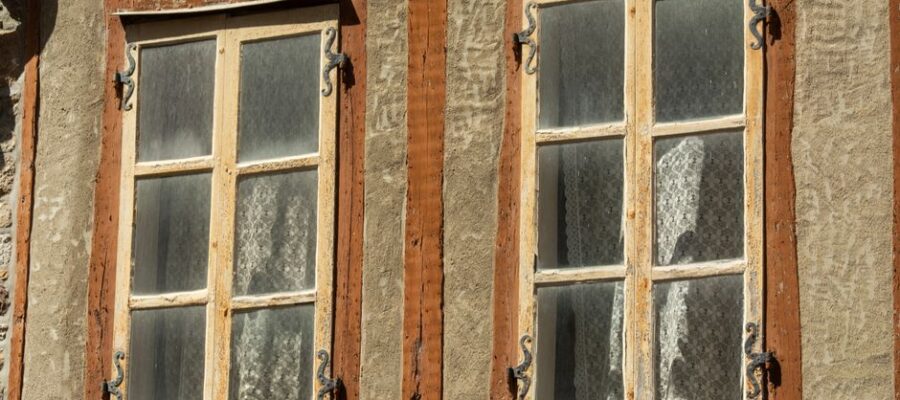 Close-up of rustic vintage windows with wooden frames on a traditional facade.