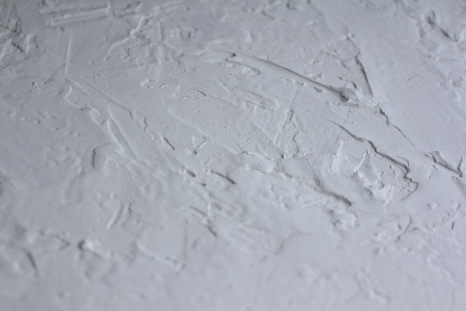 Close-up shot of a textured white plaster surface with rough details.