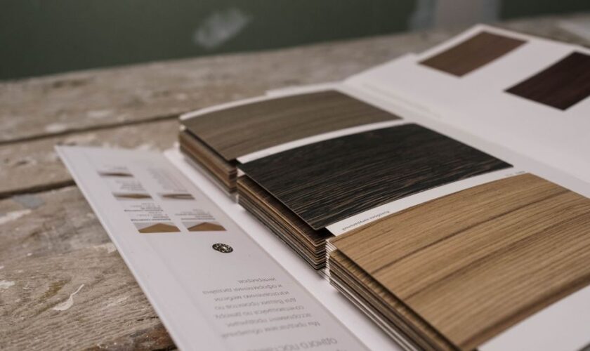 Collection of wood veneer samples displayed on a rustic wooden table indoors.