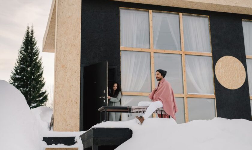 Contemporary house in a snowy setting with two people enjoying a winter day.