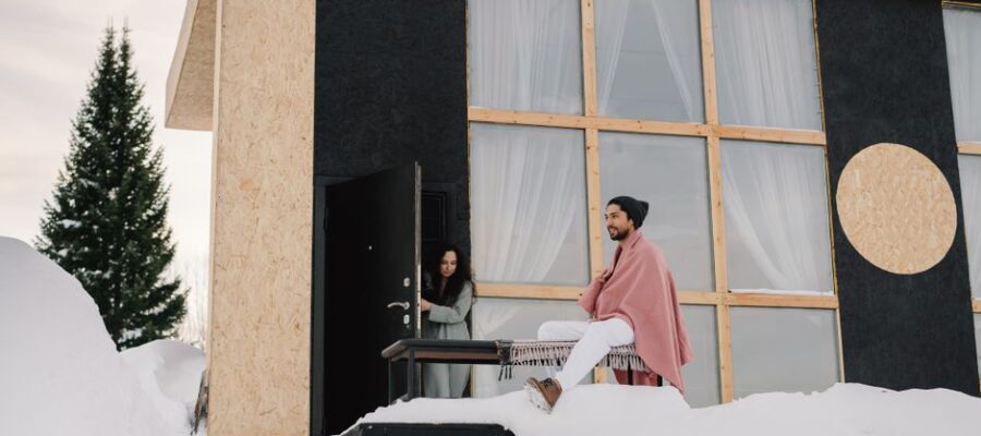 Contemporary house in a snowy setting with two people enjoying a winter day.