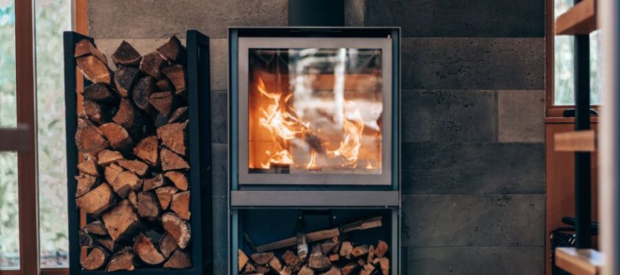Contemporary square fireplace with burning flame and fuel woods stand located in stylish modern cottage