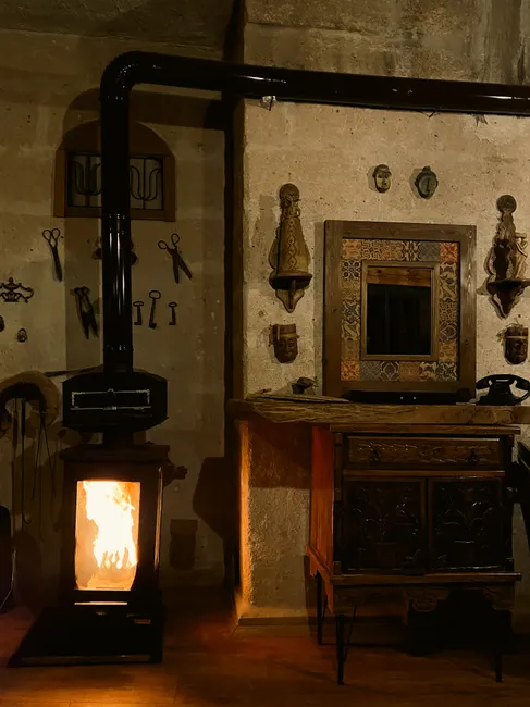 Cozy rustic room with a fireplace stove and antique decorations on the wall.