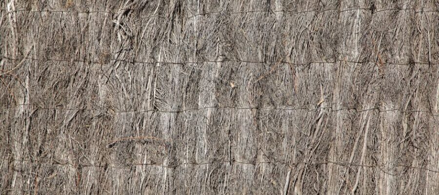 Detailed texture of a natural straw fence with woven fibers and rough surface.