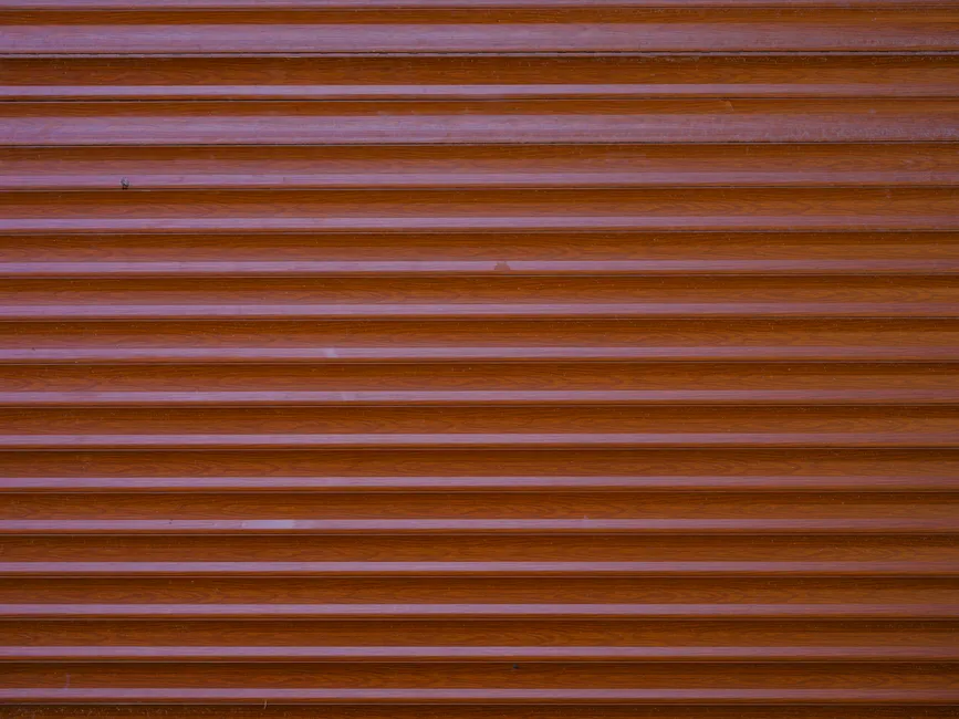 Detailed view of a brown metal roller shutter with wood-like texture for background use.