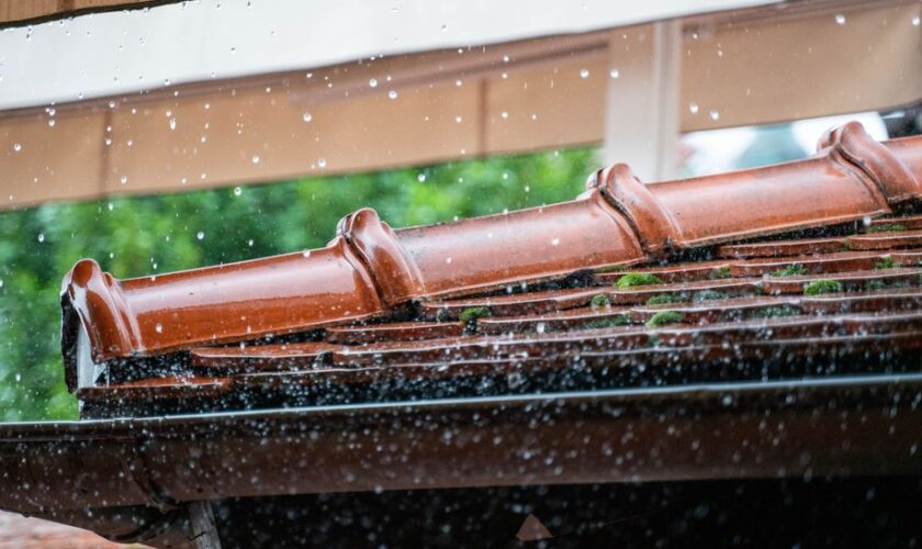 Detailed view of rain droplets cascading off a terracotta roof, capturing the essence of a rainy day.