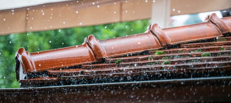 Detailed view of rain droplets cascading off a terracotta roof, capturing the essence of a rainy day.