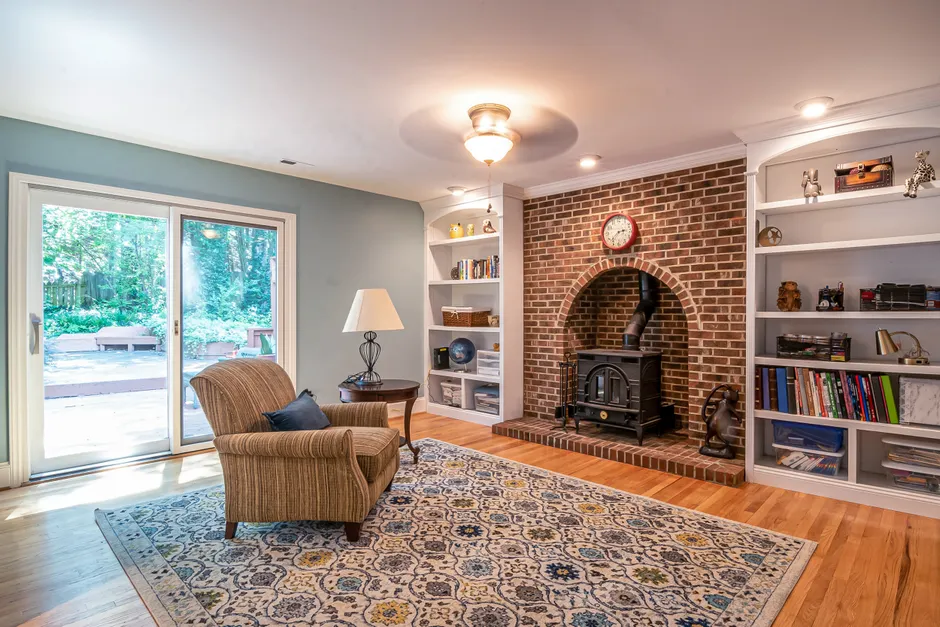Elegant living room with a brick fireplace, armchair, and large sliding glass doors to a patio.