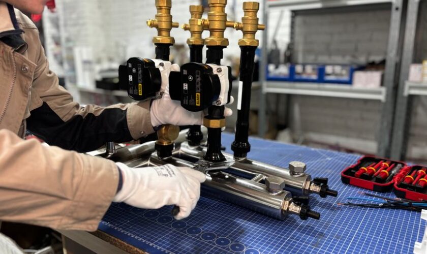 Engineer assembling a piping system for industrial heating, featuring valves and control units.