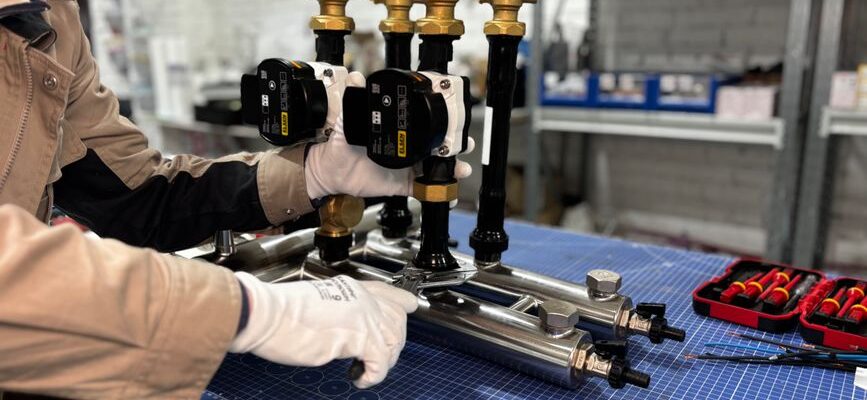 Engineer assembling a piping system for industrial heating, featuring valves and control units.